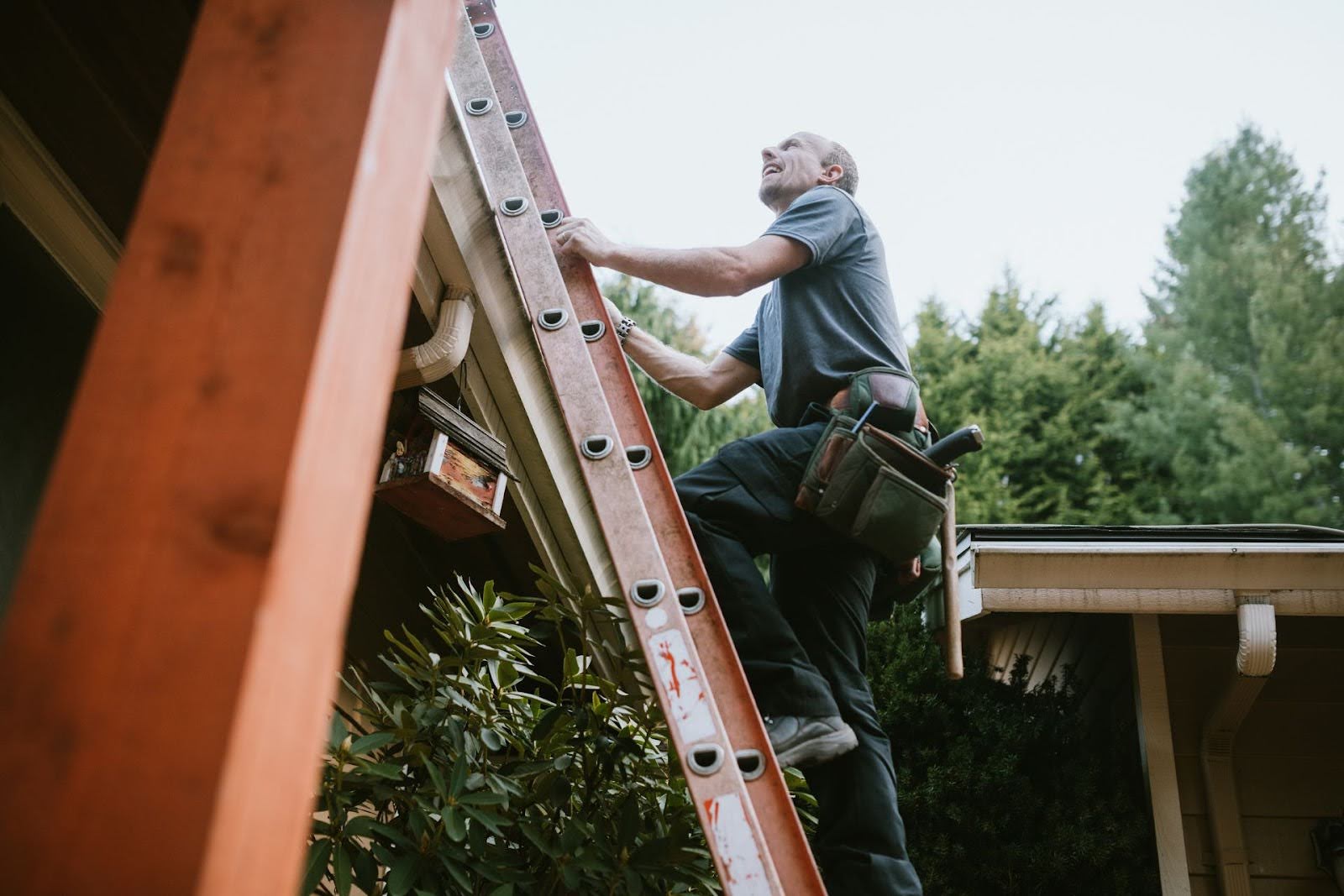 A man is climbing a ladder to reach his roof.