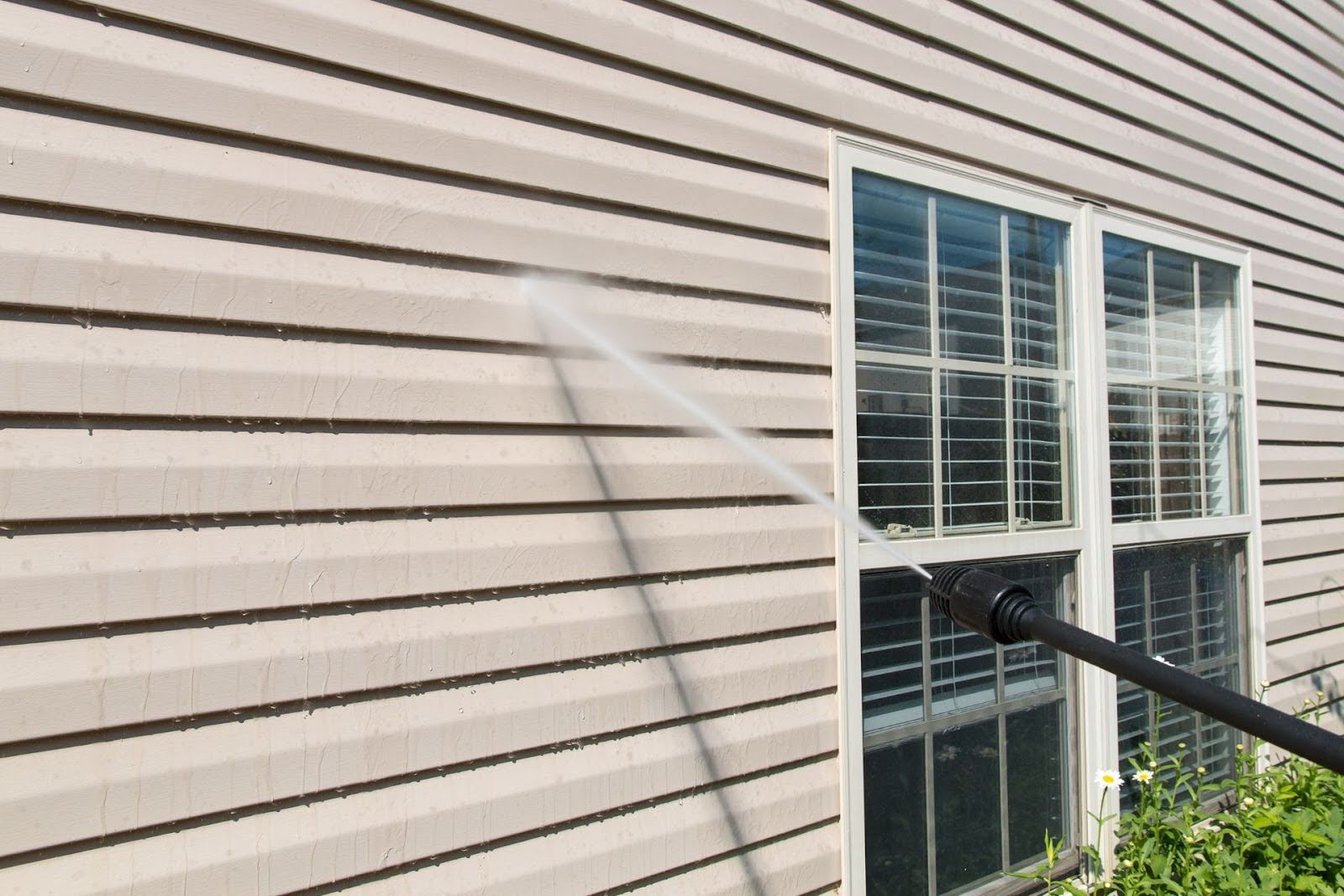 A steel siding is being pressure washed.